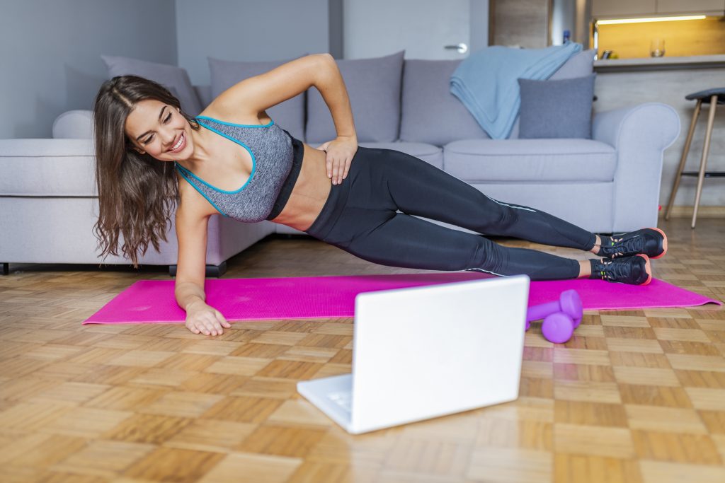 Young Woman Exercising At Home In A Living Room