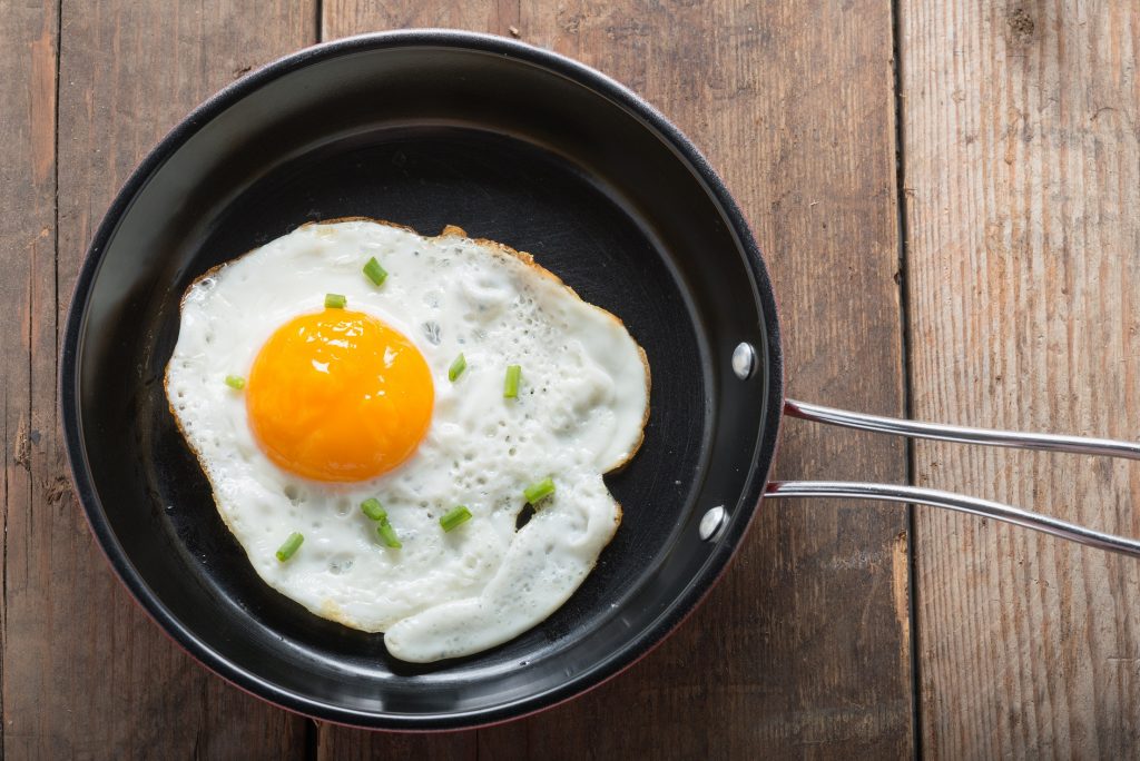 Fried,eggs,in,pan,with,handle,on,table,,top,view